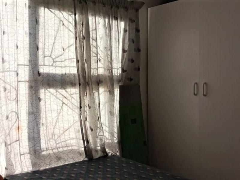A bedroom featuring a built-in wardrobe and window security bars, offering functional storage and basic security features.