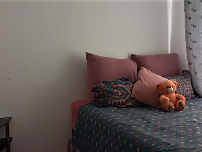 A bedroom featuring a window with curtains and plain wall finishes.