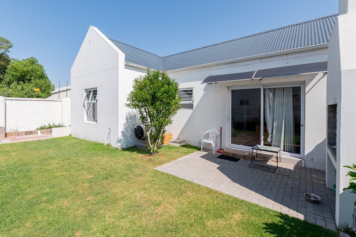 Rear exterior view of the property featuring a paved patio, built-in braai, sliding door access, and a private garden area.