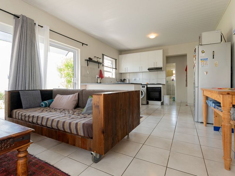 Open-plan living and kitchen area featuring tiled flooring, white cabinetry, and direct access to the outdoors via a sliding glass door.
