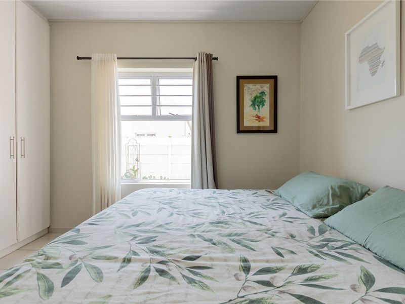 A well-maintained bedroom featuring neutral walls, tiled flooring, and a built-in wardrobe with clean, modern finishes.