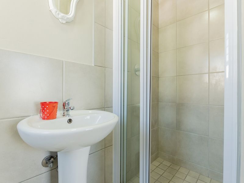 A functional bathroom featuring a pedestal basin with a mixer tap and a tiled shower enclosure.