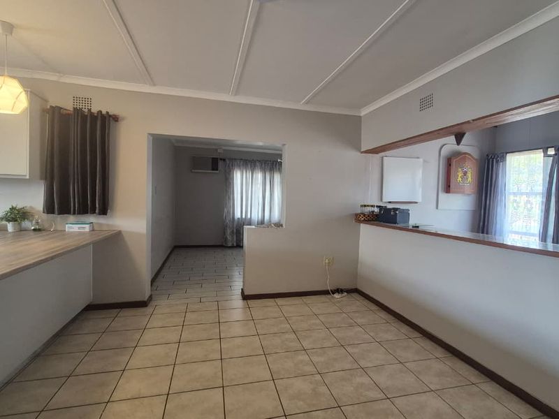 Open plan living area featuring tiled flooring, a breakfast bar, and a convenient pass-through window connecting to the kitchen space.