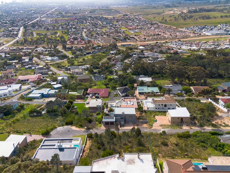 An aerial view of a residential neighborhood featuring a mix of developed properties, vacant land plots, and surrounding natural vegetation.