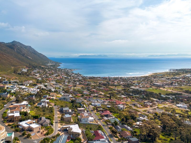 An expansive aerial view of a coastal residential neighborhood, showcasing the surrounding mountain range and ocean coastline.