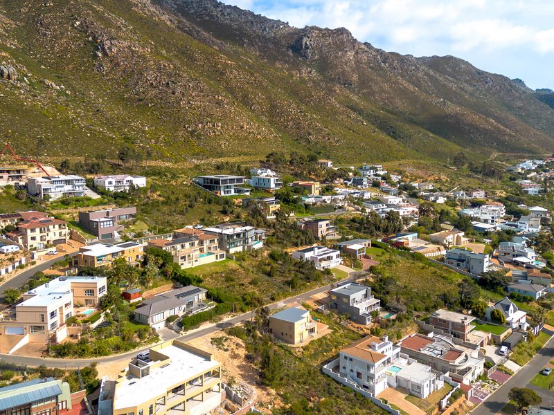 An aerial view of a residential neighborhood nestled against a mountain range, showcasing the surrounding landscape and property layout.