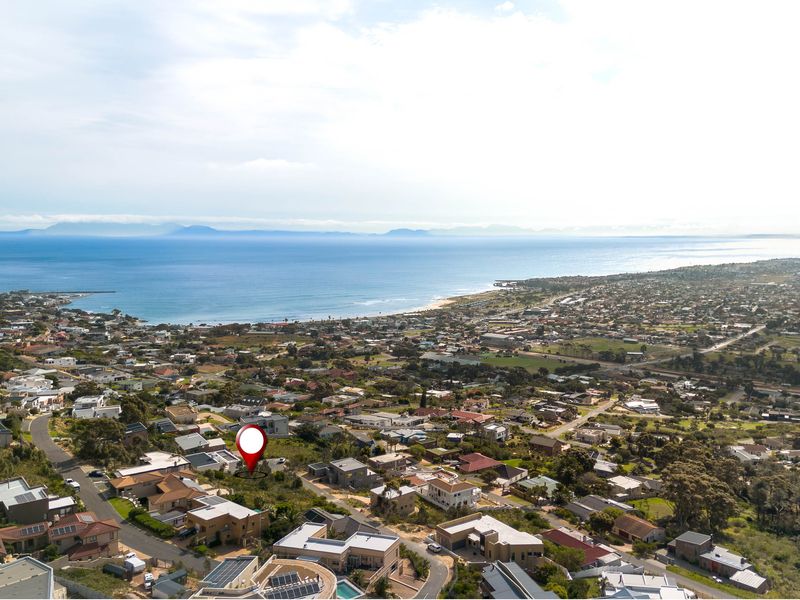 An aerial view of a residential neighborhood situated along the coastline, highlighting the property location and surrounding landscape.