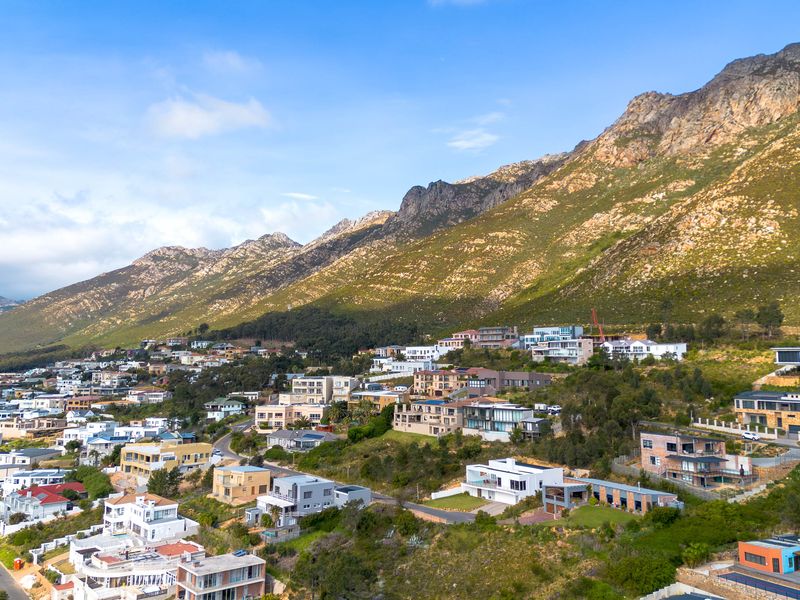 An aerial view of a residential hillside neighborhood nestled against a scenic mountain range.