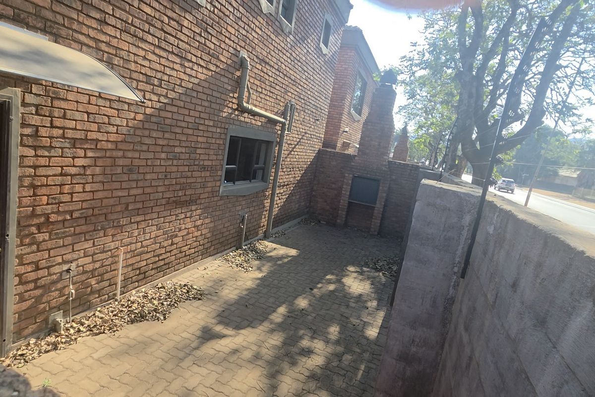 A private rear courtyard featuring brick wall construction, paved flooring, and a built-in outdoor braai area, offering potential for an entertainment space.