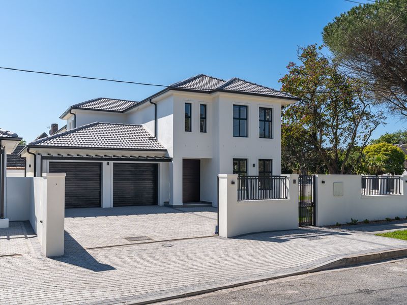 Modern double-story residence featuring a paved driveway, double garage, and secure boundary wall with gated entrance.