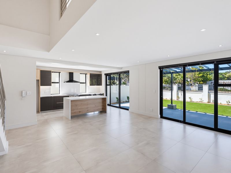Spacious open-plan living and kitchen area featuring modern cabinetry, a central island, and large sliding doors opening to a private garden.