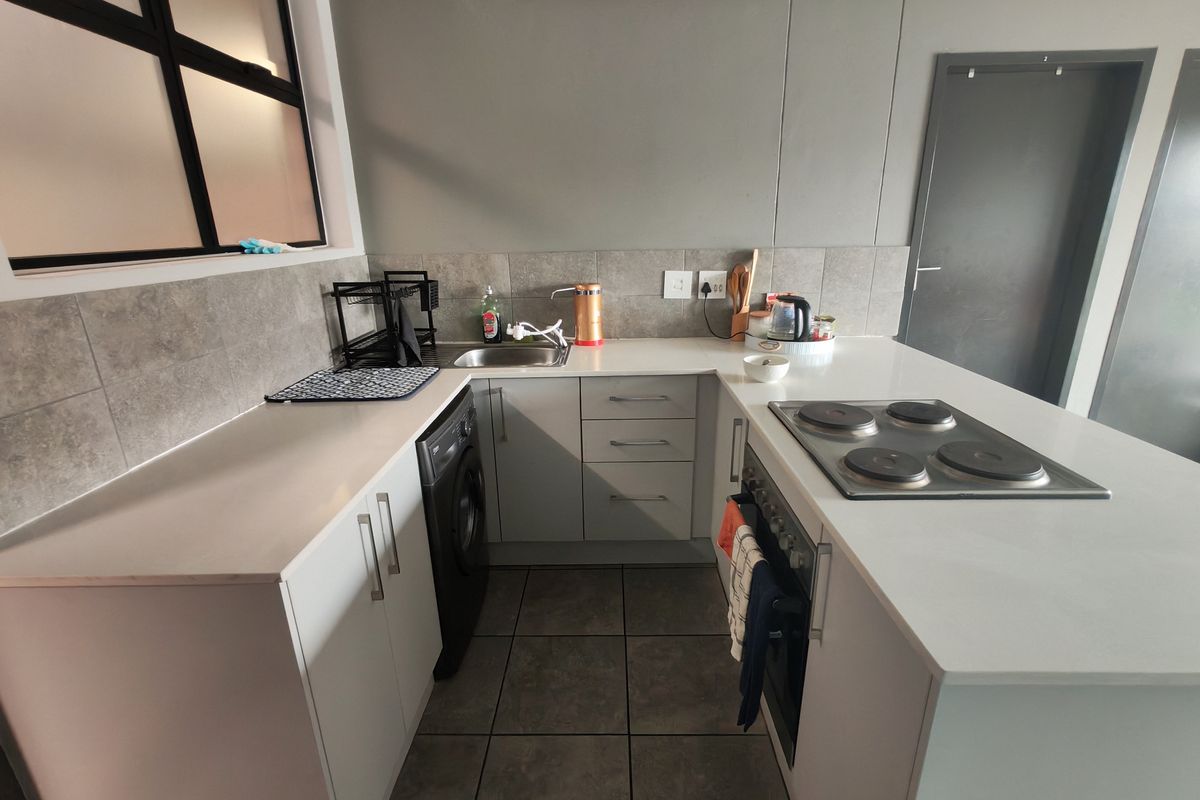 Modern kitchen featuring sleek white cabinetry, stone countertops, integrated appliances, and a functional layout with a built-in hob and oven.