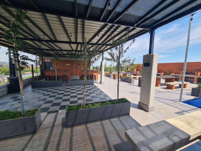 Spacious covered rooftop patio featuring a brick bar, built-in concrete seating, and integrated planters, offering an ideal outdoor entertainment area.