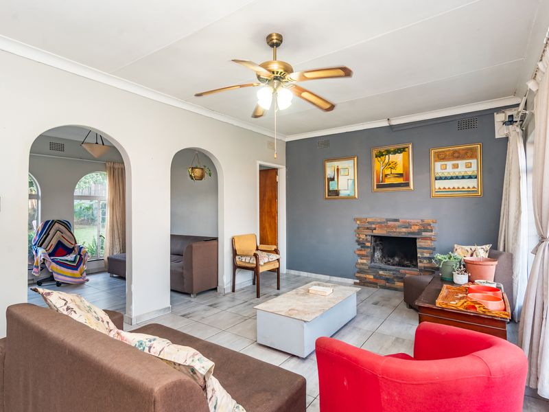 Spacious living room featuring a stone-clad fireplace, tiled flooring, and distinctive archways leading to an adjacent area, offering a comfortable and functional layout.