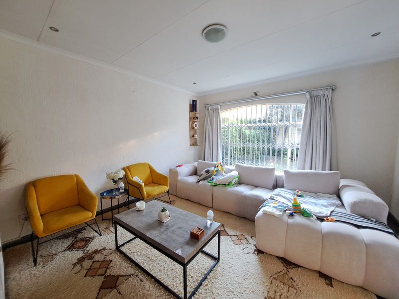A comfortable living room featuring security bars on the window, recessed downlighting, and a neutral color palette.