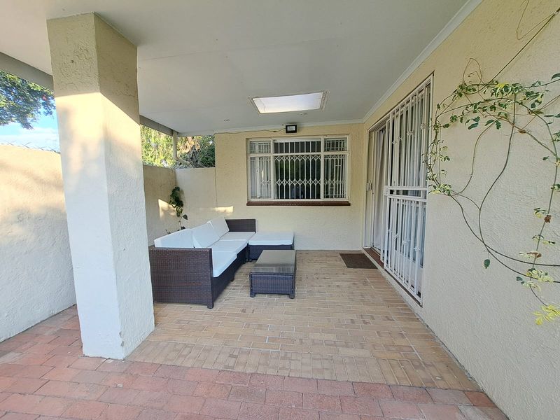 A covered patio area featuring brick paving, a skylight, and secure window and door access, providing a functional outdoor living space.