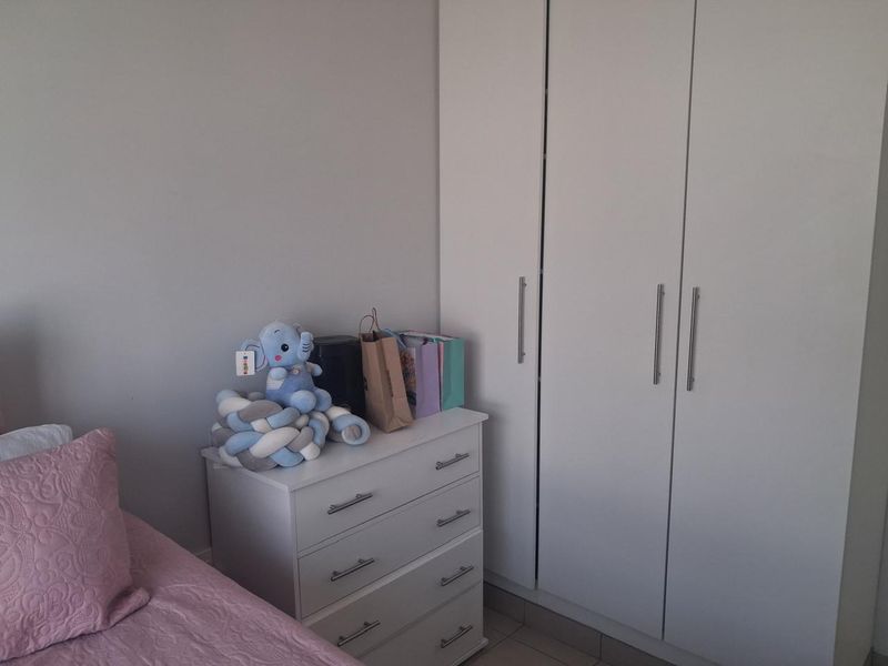 A bedroom featuring a white built-in wardrobe with modern handles, providing ample storage space.
