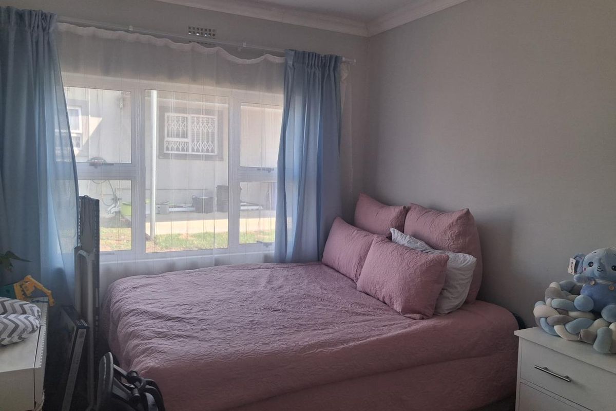 A bedroom featuring a large window with natural light and decorative cornice detailing.