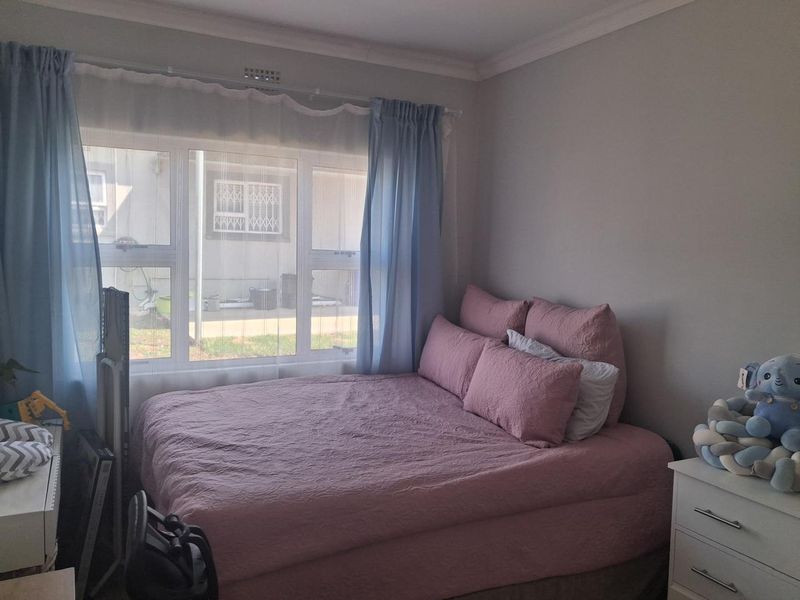 A bedroom featuring a large window with natural light and decorative cornice detailing.