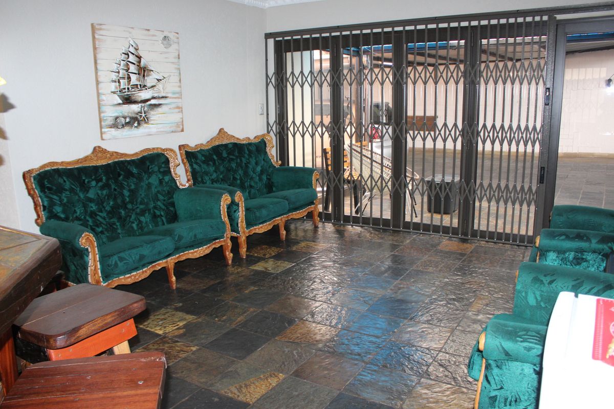 Living room featuring slate tile flooring and large sliding glass doors with integrated security gates providing access to the outdoor area.