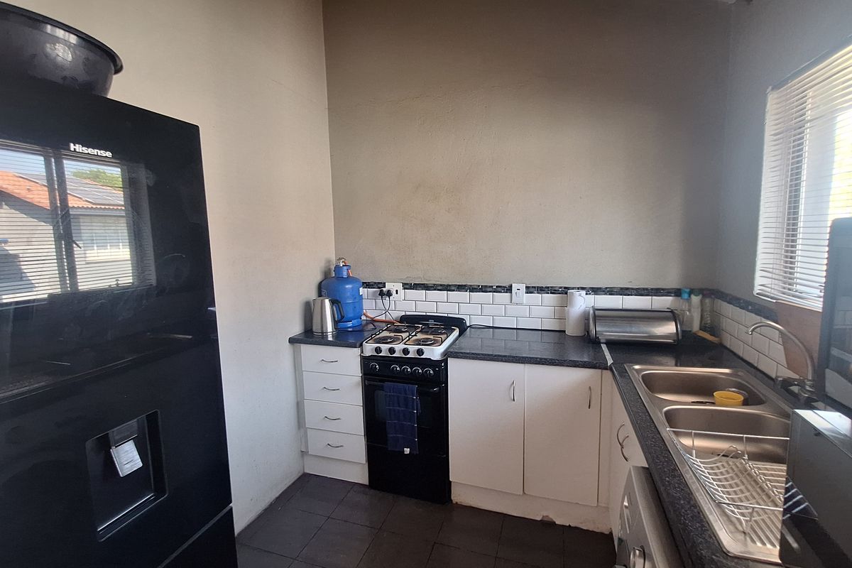 Compact kitchen featuring a gas stove, double bowl sink, subway tile backsplash, and functional built-in cabinetry with laminate countertops.