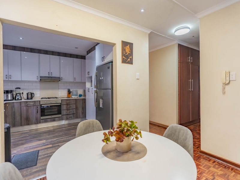 Open plan kitchen featuring modern two-tone cabinetry, subway tile backsplash, and integrated appliances, flowing into a dining area with classic parquet flooring.
