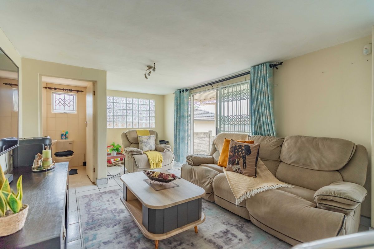 A living room featuring tiled floors, a glass block window, and sliding doors leading to an outdoor area, with an adjacent bathroom entrance.