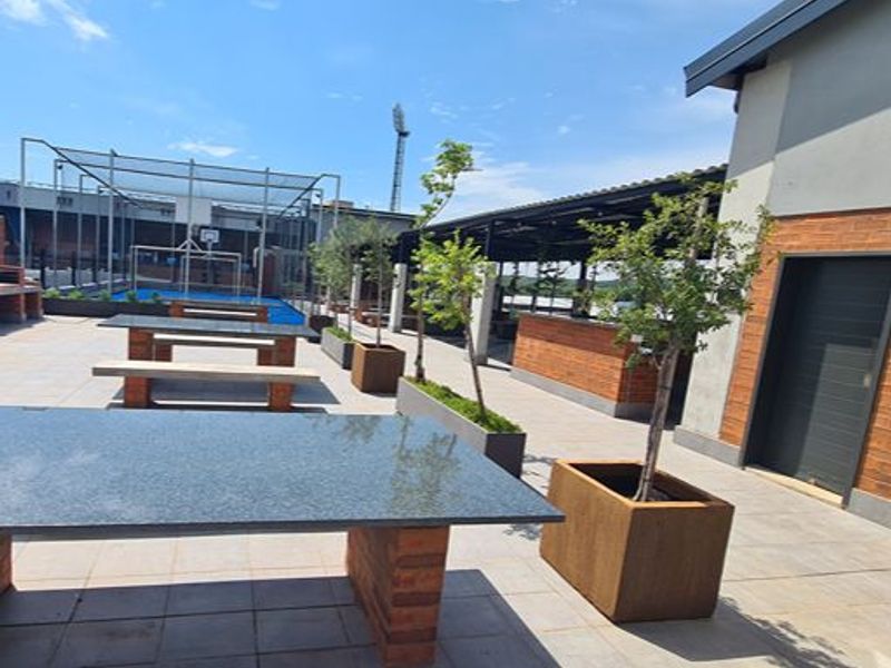 Spacious outdoor patio area featuring built-in brick seating, granite-topped tables, and a covered pergola, ideal for social gatherings and outdoor entertainment.