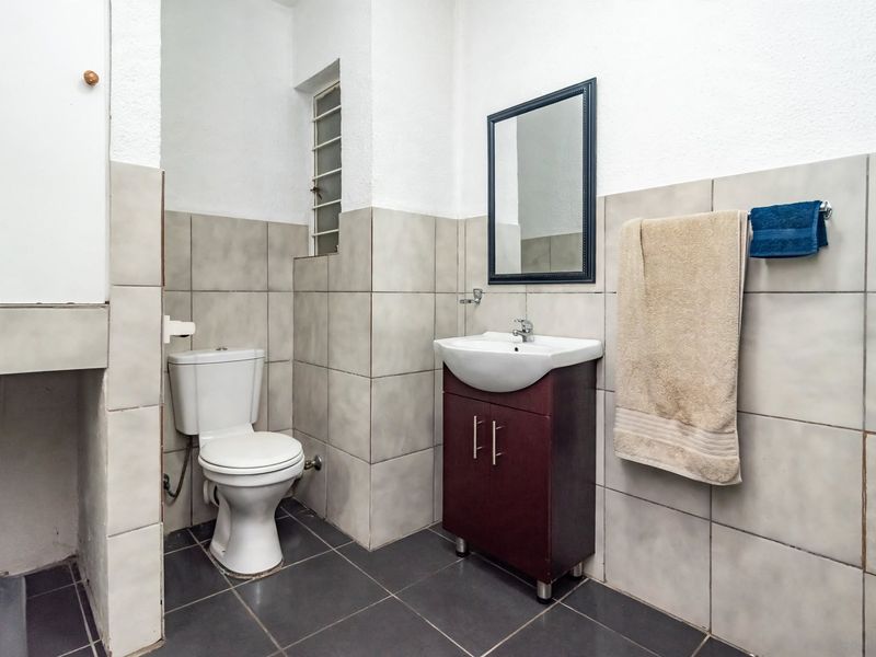 A functional bathroom featuring a vanity cabinet with a basin, a standard toilet, and neutral wall and floor tiling.