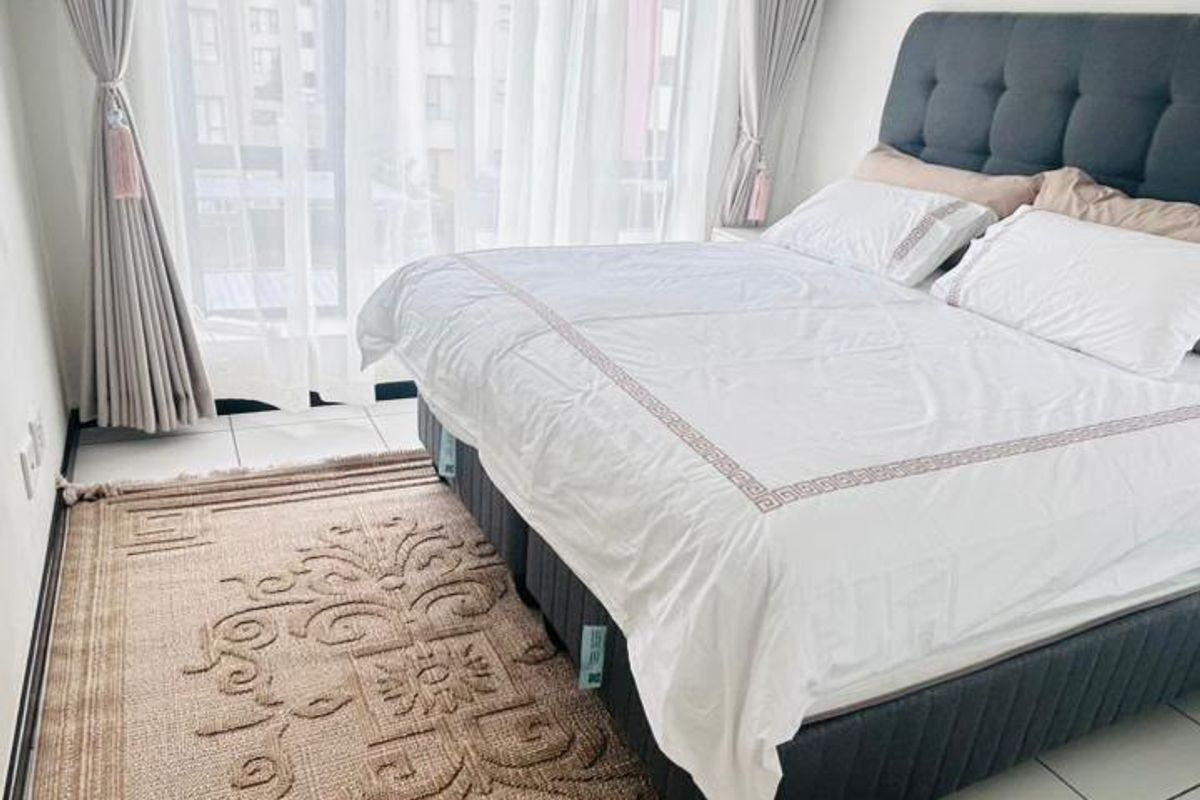 A bright and well-maintained bedroom featuring tiled flooring, recessed lighting, and a large sliding glass door providing access to the exterior.