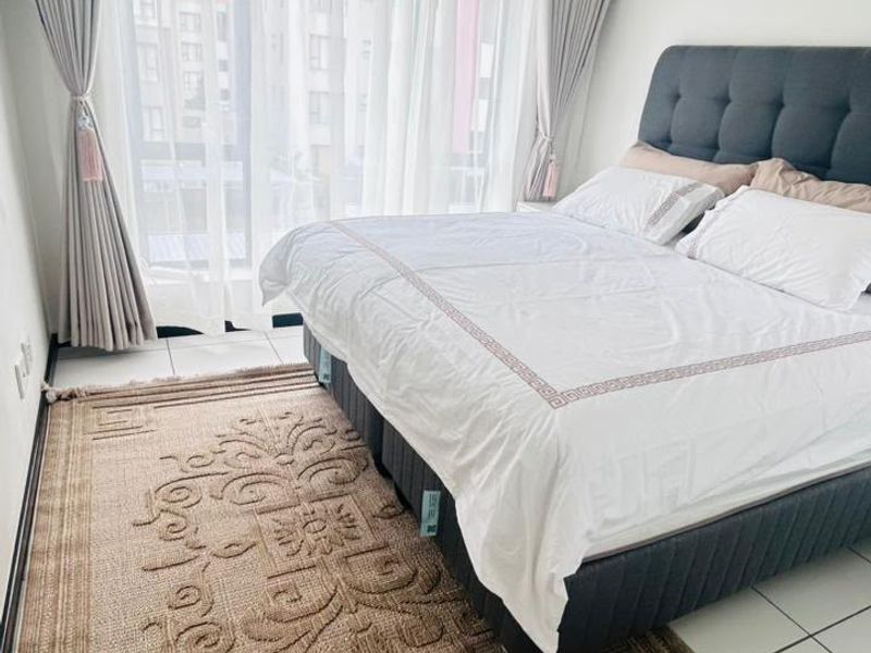 A bright and well-maintained bedroom featuring tiled flooring, recessed lighting, and a large sliding glass door providing access to the exterior.
