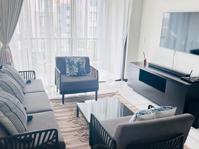 A bright and modern living room featuring tiled flooring and large sliding glass doors that provide access to the balcony.