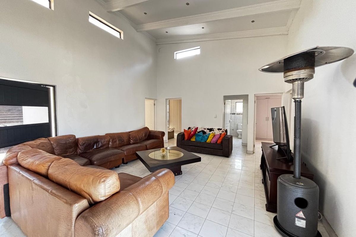 Spacious living room featuring high vaulted ceilings, clerestory windows, and tiled flooring, offering a bright and open layout.