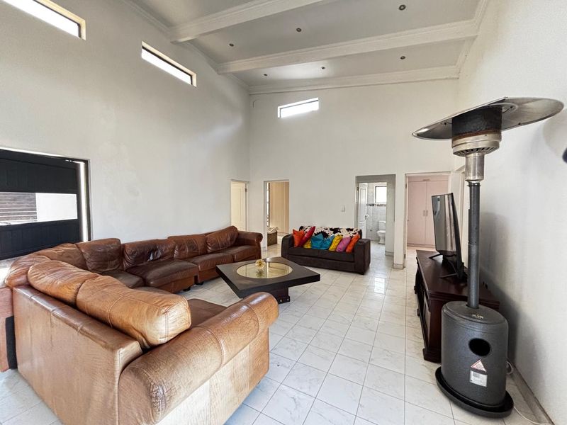 Spacious living room featuring high vaulted ceilings, clerestory windows, and tiled flooring, offering a bright and open layout.
