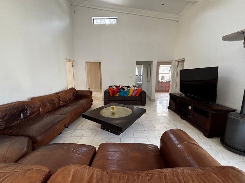 Spacious living room featuring high vaulted ceilings, tiled flooring, and a clerestory window, providing an open and airy atmosphere.