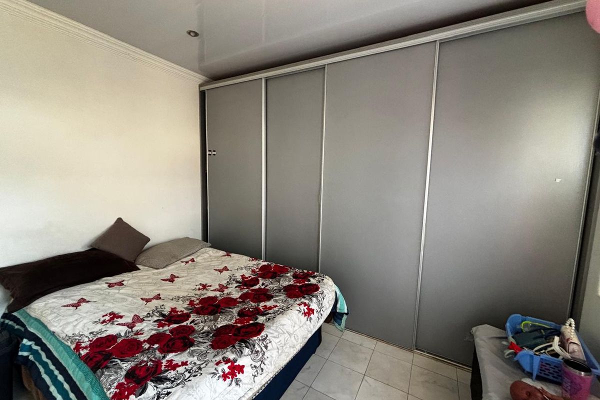 A bedroom featuring a large built-in sliding door wardrobe, tiled flooring, and recessed ceiling lighting.
