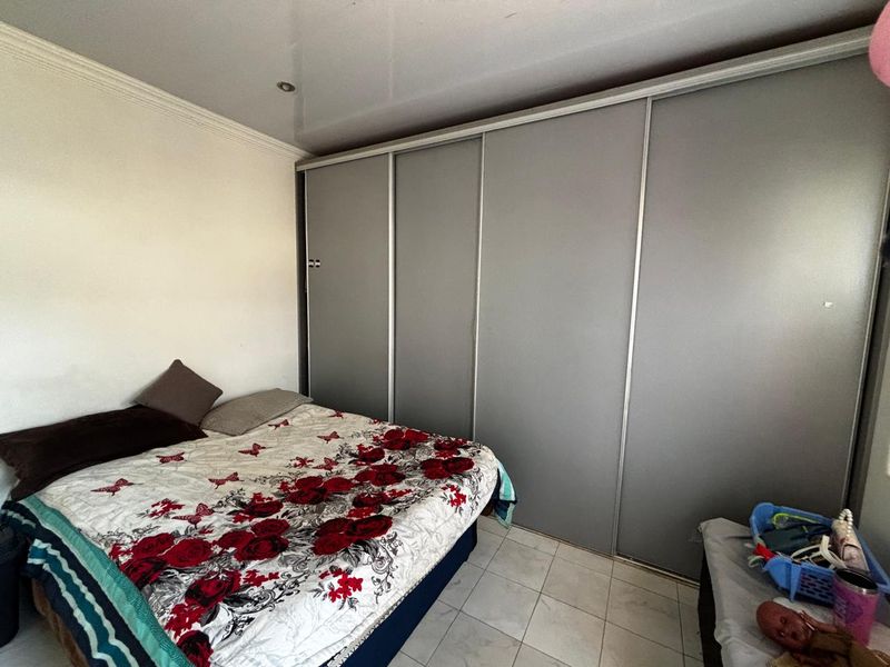 A bedroom featuring a large built-in sliding door wardrobe, tiled flooring, and recessed ceiling lighting.
