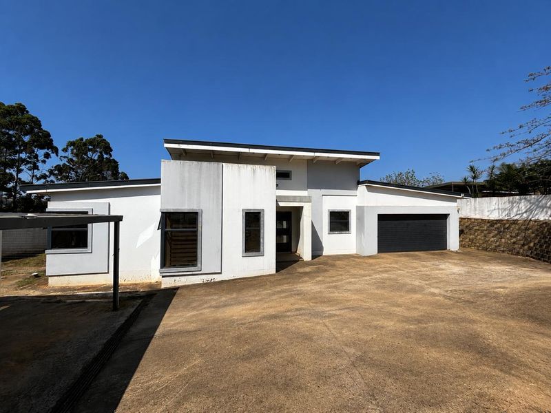 Front elevation of a modern house featuring a concrete driveway, single garage, and clean architectural lines under a clear blue sky.
