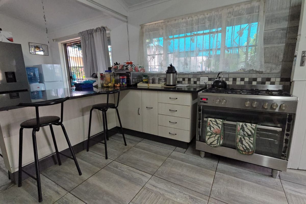 Functional kitchen featuring a breakfast bar, tiled flooring, and a stainless steel gas stove with oven.