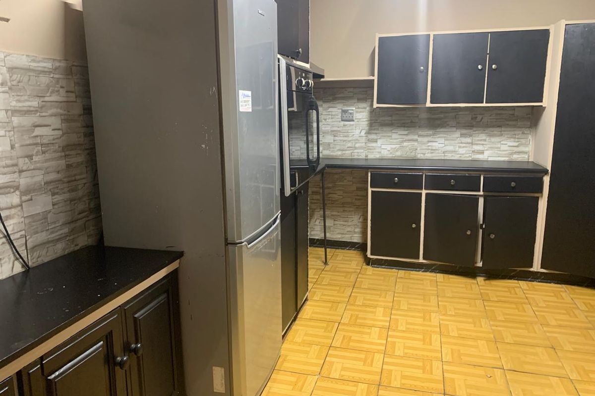 A functional kitchen featuring dark cabinetry, built-in oven, tiled backsplash, and tiled flooring, offering potential for a modern renovation.