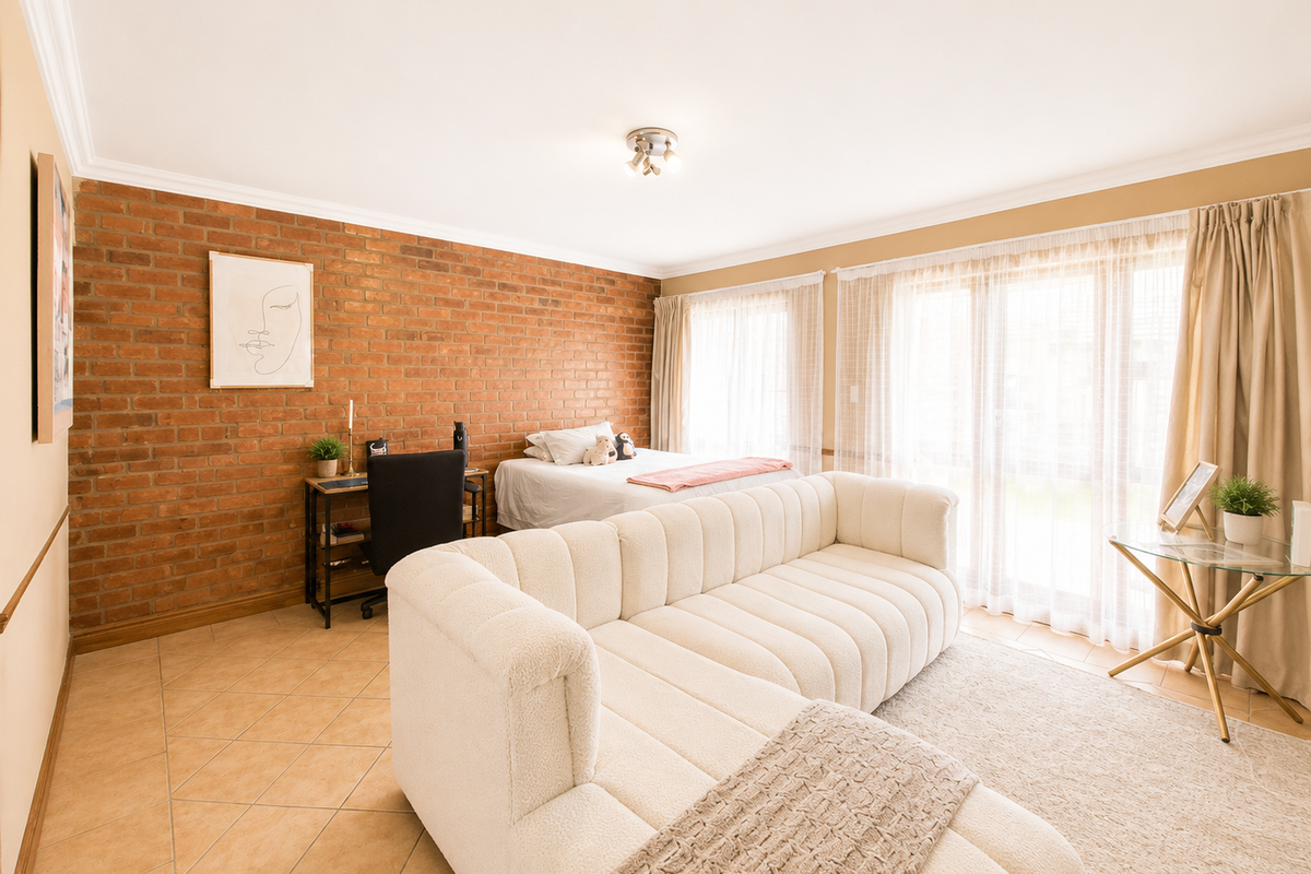 Spacious bedroom featuring an exposed brick feature wall, tiled flooring, and large sliding glass doors providing ample natural light.