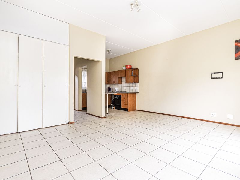 Open-plan living area featuring tiled flooring, built-in storage cupboards, and a compact kitchen with wooden cabinetry and integrated oven.