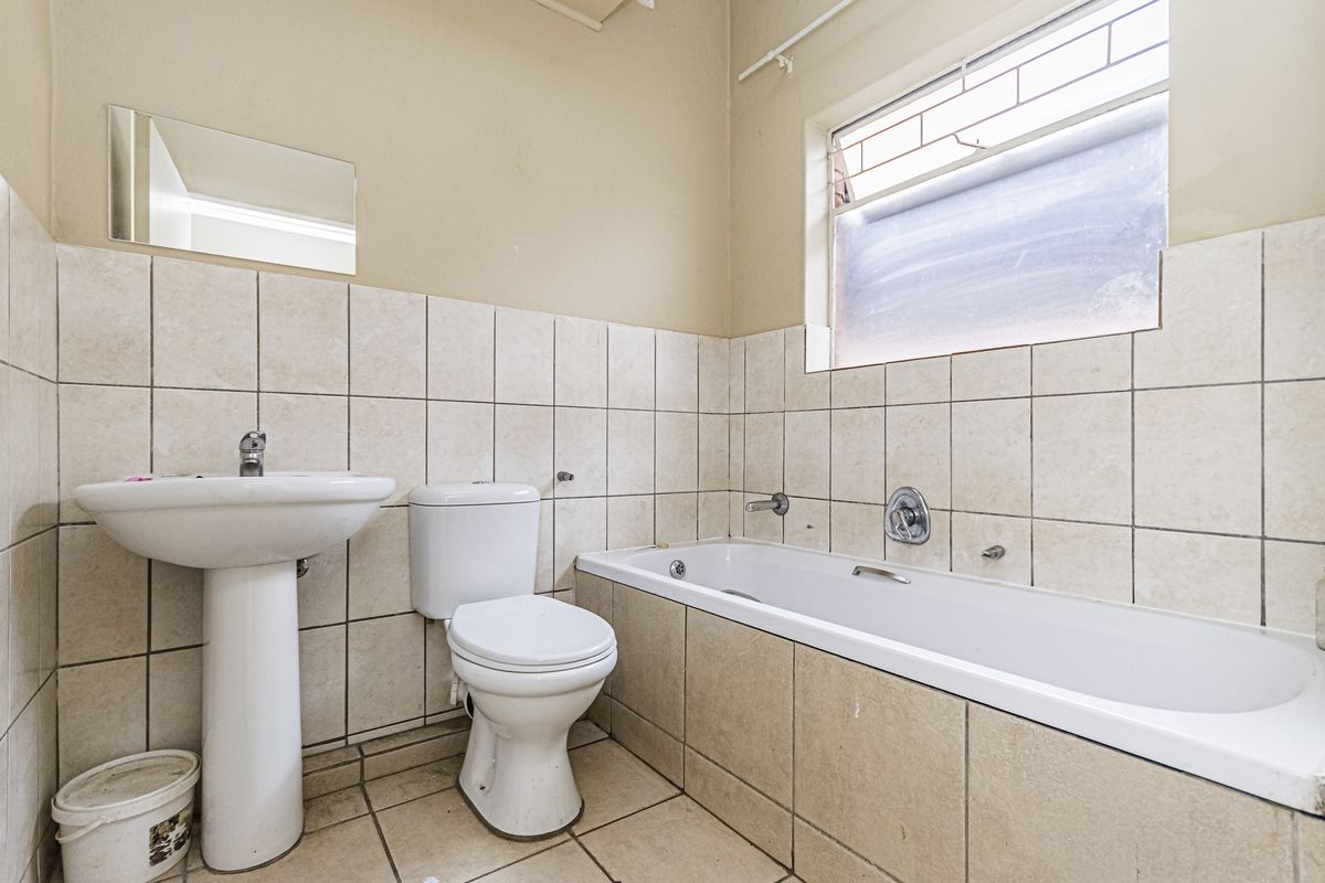 A dated bathroom featuring a pedestal basin, standard toilet, and bathtub with tiled walls and flooring, offering potential for modernization.