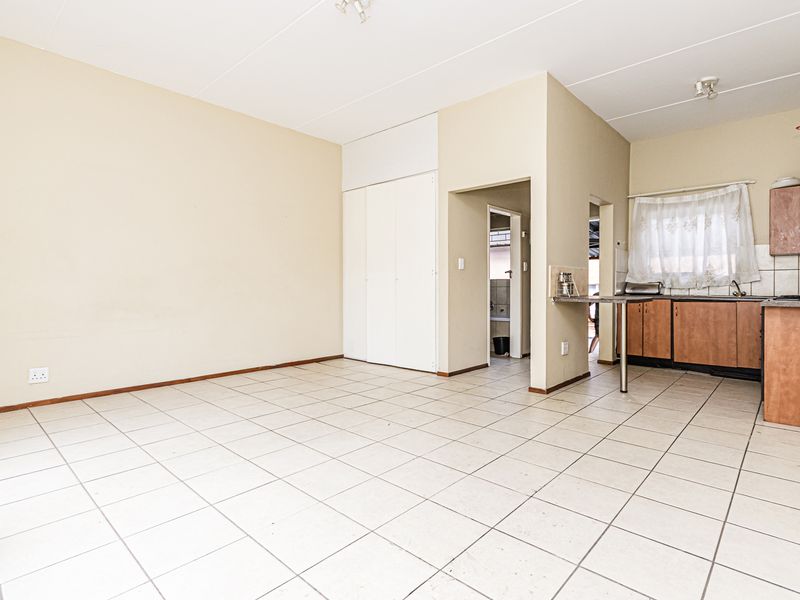 Open-plan living area featuring tiled flooring, a functional kitchen with built-in cabinetry, and a separate built-in closet for additional storage.