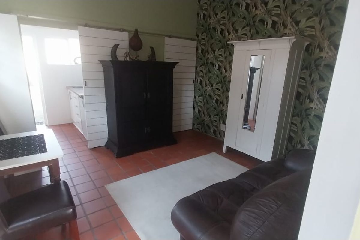 Open plan living area featuring terracotta floor tiles and sliding barn doors, providing a functional layout with access to the adjacent kitchen space.