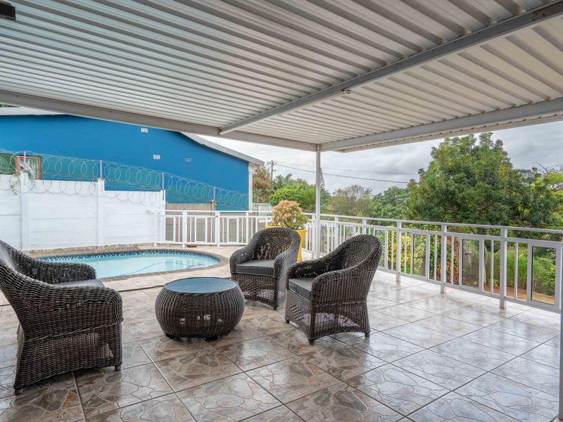 Covered outdoor patio area featuring tiled flooring, protective railing, and direct access to an adjacent swimming pool.