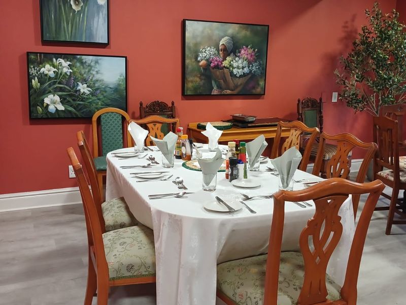 A formal dining room featuring red walls, crown molding, and light-toned laminate flooring, providing a warm and traditional setting for meals.