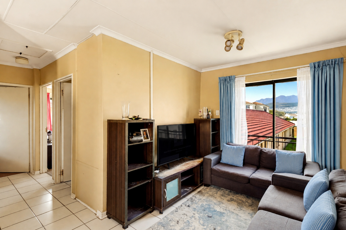A living room featuring tiled flooring, coved ceilings, and a sliding glass door providing natural light and access to an outdoor balcony area.