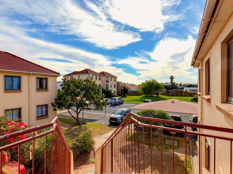 Exterior view from an upper level staircase overlooking the apartment complex grounds, parking area, and surrounding neighborhood.