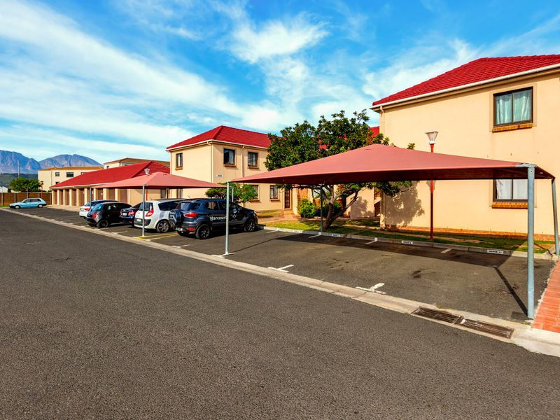 Exterior view of the apartment complex featuring paved parking areas with shade cloth carports and well-maintained building facades.